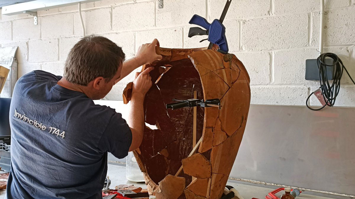 A photo of Tom Cousins piecing together the vase